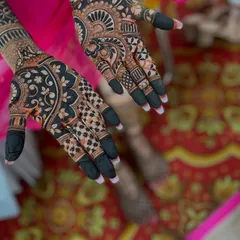 The beauty of a dark, rich henna stain. This design showcases a striking contrast with bold floral and paisley motifs, and the fingertips are dipped for a traditional look.