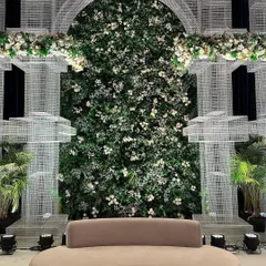 A modern lounge area set against a backdrop of a massive green wall. The clean lines of the furniture contrast beautifully with the organic feel of the floral decor.