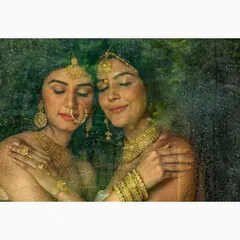 A moody and atmospheric jewellery shoot, photographed through a textured, rain-streaked surface. This technique creates an intimate and artistic feel, focusing on the emotion and the golden glow of the traditional Indian jewellery.