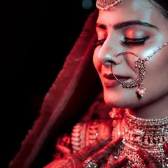 A close-up bridal shot focusing on the beautiful makeup and jewelry. The warm red light adds a touch of drama and romance, highlighting the glow of the bride on her wedding day.