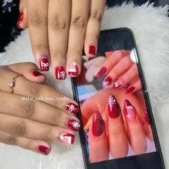 A still photo of the finished Christmas nail art. Each nail has a different festive element, like a snowflake or a Santa hat, all hand-painted in classic red and white.