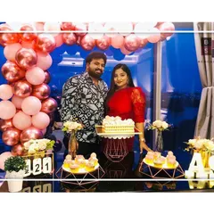 A beautiful portrait from a first-anniversary celebration we decorated. The couple stands before the full setup, featuring a stunning balloon arch and a dessert table filled with treats, all designed to celebrate their love.