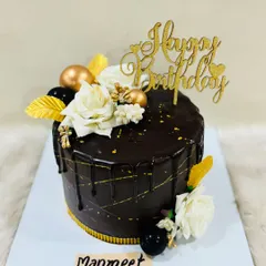 A classic chocolate truffle cake with a glossy drip, gold accents, and elegant white roses. A sophisticated choice for any celebration.