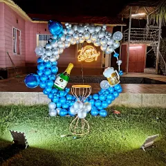 A fun birthday party by a house, with a blue and silver balloon ring on the lawn, perfect for an evening celebration.