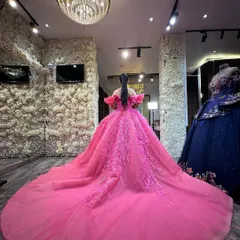 The back view of this gorgeous rose pink ball gown, showing off its long, dramatic trail and floral embroidery inside my studio. The flower wall and chandelier add to the luxurious experience.