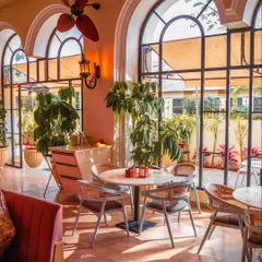 Sunlight streams through the large arched windows, illuminating the space for a perfect daytime gathering. This bright and airy setting is ideal for brunches, workshops, or corporate lunches.