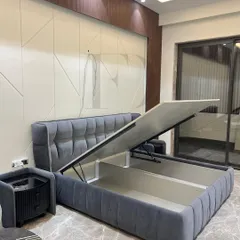 This modern bed features a tufted, winged headboard in a sophisticated grey velvet. The front-lift hydraulic mechanism reveals ample under-bed storage, combining luxury with practical functionality.