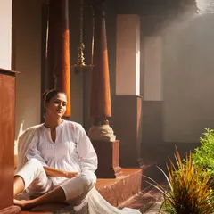 This is the feeling of post-treatment bliss. Here, a guest soaks in the serene, misty atmosphere of our heritage verandah after a rejuvenating Ayurvedic therapy session. This moment of quiet reflection is an essential part of the healing process, allowing the body and mind to absorb the benefits of the treatment.