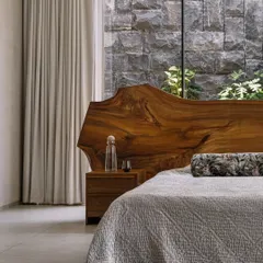 In our GAIA project in Chennai, we designed this master bedroom to be a serene retreat. The live-edge wood headboard brings a raw, natural element indoors, set against a rugged stone wall that connects the space to the earth, reflecting our modern organic and Wabi-Sabi design principles.