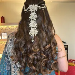 A beautiful combination of open curls and a jeweled hairpiece. This half-up style keeps the hair away from the face while still showcasing its length and volume, perfect for an engagement or reception.