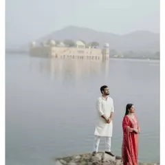A serene portrait taken at Jal Mahal in Jaipur. The misty morning and the distant water palace create a dreamy, almost painterly backdrop for this couple, dressed in beautiful traditional Indian attire.