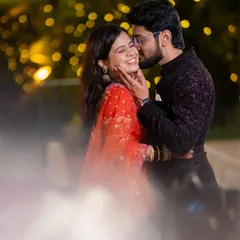 A playful and affectionate moment captured at dusk, with the groom kissing the bride's cheek, making her laugh.