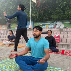 A student in deep meditation, with me guiding the class in the background during our Haridwar session.