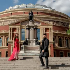 A wide-angle shot capturing the magnificent architecture of the Royal Albert Hall. The couple stands on the steps, creating a sense of scale and grandeur for their London pre-wedding shoot.
