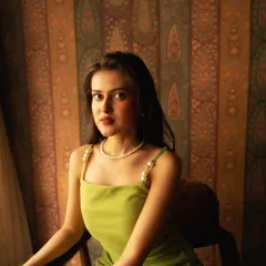 A simple, elegant portrait against a beautifully patterned backdrop. The natural light from the window provides a soft, flattering illumination.