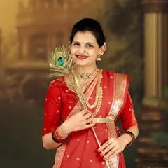 A beautiful solo portrait celebrating tradition. The mother-to-be is dressed in a stunning red saree, holding a peacock feather, which adds a touch of divine symbolism to the maternity photo.