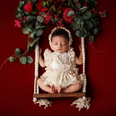 This elegant swing prop, adorned with a floral garland against a rich red backdrop, creates a beautiful and artistic composition.
