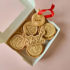 A box of my Christmas-themed savoury pies. Each pie has a different festive design, like a Santa, a Christmas tree, or a gingerbread man, and comes with a 'Merry Christmas' cookie.