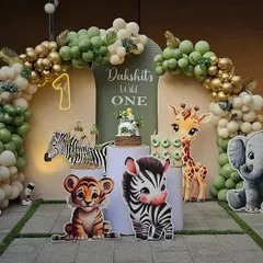 For little Dakshit's first birthday, we created a "Wild One" jungle safari theme. This adorable photo corner features cute animal cutouts, a lush balloon arch in sage green and gold, and a custom cake, setting the stage for a fun and memorable celebration.