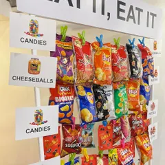 A custom snack wall with the sign "EAT IT, EAT IT" was a fun and interactive element at 'The Office' themed party. We clipped various chips and snacks for guests to grab, just as you might see in a Dunder Mifflin celebration.
