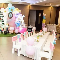 An Alice in Wonderland-themed kids' table, with cute white chairs and pastel-colored decor.