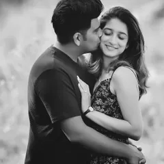 A sweet kiss on the cheek. This classic pose becomes even more romantic and timeless in black and white, highlighting the affection between the couple.