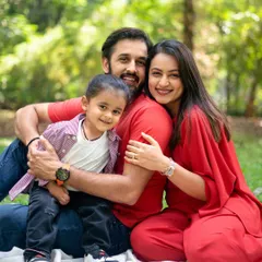 A beautiful, warm hug during an outdoor family session. The lush green background and natural sunlight create a perfect setting for this loving family portrait.