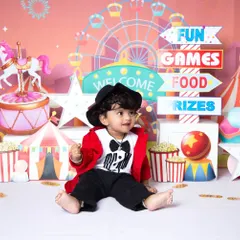 Welcome to the carnival! This vibrant, fully-styled setup is perfect for a fun-filled milestone session, complete with a colorful ferris wheel, popcorn, and a tiny ringmaster outfit.