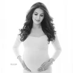 A serene and gentle solo portrait. Black and white enhances the soft light and the quiet emotion as this mother-to-be gazes lovingly at her bump.