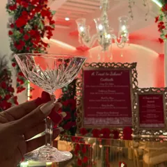Raising a premium crystal coupe glass to a beautiful celebration. The bar setup, with its ornate menu and floral decor, created the perfect backdrop for this elegant Navjote.