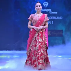 The model walks the runway in the red and gold embroidered lehenga, surrounded by a dramatic mist. This piece is designed to be as powerful as it is beautiful.