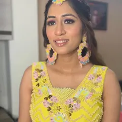 Radiant and flawless Haldi bride goals. This look features a pop of pink on the eyes to complement the bright yellow outfit and fun, colorful jewelry.