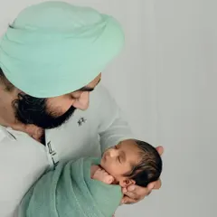 A slightly different angle showing the father's loving expression as he looks at his peacefully sleeping baby.