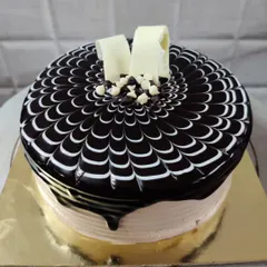 A classic chocolate truffle cake that's always a crowd-pleaser. It has a rich, glossy ganache topping with a signature spider-web design, finished with white and dark chocolate chips for extra texture.