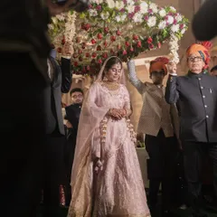The traditional bridal entry under a 'phoolon ki chadar', a moment filled with emotion and family love. We frame this shot to include the loved ones who are part of this journey.