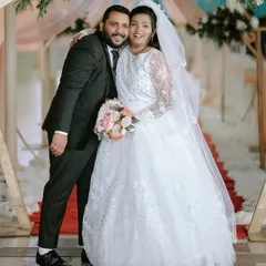 A happy moment between the bride and groom. Her makeup is soft and romantic, with a lovely pink bouquet that adds a touch of colour to her classic white gown.