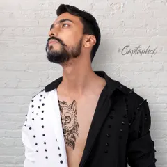 An unbuttoned, stylized shot designed to showcase a model's physique and tattoos alongside the fashion. This type of edgy studio portrait adds a layer of personality and confidence to a professional portfolio.