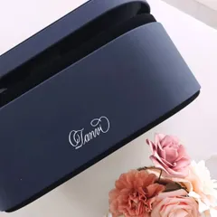 A top down view of the personalized Dyson case, surrounded by delicate flowers. The simple, elegant script of the name 'Tanvi' makes this a truly special and luxurious self-care accessory.