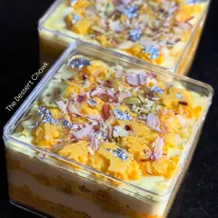 A pair of Rasmalai Cake Tubs, ready to be delivered. You can see the layers of cake and cream, topped with rasmalai chunks, nuts, and edible silver leaf.