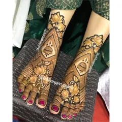 This bridal foot design features bold lotus flowers and traditional jhumka motifs. The use of negative space makes the central patterns pop, creating a striking effect.