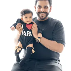 Daddy's little girl! A proud father holds his daughter, who is wearing an adorable "I ❤️ Papa" onesie. A perfect portrait for Father's Day or any day.