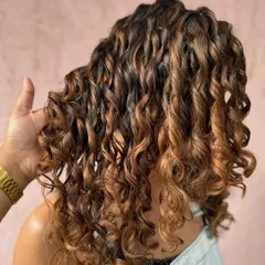 Caramel kissed curlylocks. These beautiful curls are enhanced with warm, caramel tones using a non-bleach formula for a healthy, glossy finish.