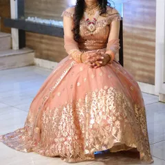 A full view of our peach off-shoulder gown, showcasing its impressive flare and intricate gold leatherwork. This modern rental piece is ideal for sangeet nights, receptions, or for a sister of the bride or groom.