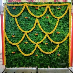 This unique and eco-friendly backdrop is made entirely of fresh betel leaves, accented with marigold flower garlands. It's a beautiful and fragrant option for an ear piercing ceremony or other traditional functions.