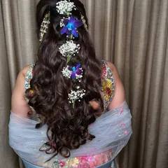 A hairstyle fit for a princess. For her Mehendi look, we adorned her long curls with fresh flowers, adding a touch of natural beauty.