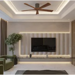 The TV wall in the same guest bedroom features a curved, fluted stone panel with integrated LED lighting. This soft architectural element adds a sense of fluidity and style, complemented by the plush green armchairs.