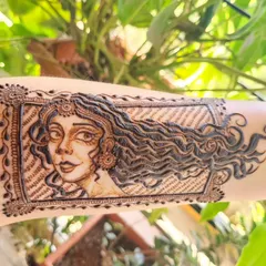 This design started as a random doodle and turned into one of my favorite artistic pieces. The portrait of a woman with long, flowing hair is framed to look like a beautiful piece of art on the arm.