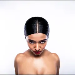 A dramatic, high-angle shot that adds an editorial edge to a commercial beauty campaign. The model's direct, intense gaze combined with the sleek hair and bold red lip creates a powerful and memorable image. This angle is unconventional and designed to grab attention.