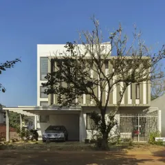 This completed home in South Bangalore, seen here behind a beautiful Kachnar tree, features a modern elevation with strong vertical lines. The design provides privacy while allowing ample natural light into the living spaces.