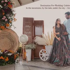 We love planning pre-wedding celebrations at stunning destinations like Wayanad. Here, the couple poses against a rustic-chic decor setup we created, with the mountains and lake providing a spectacular natural backdrop.